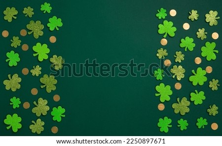 St. Patrick's Day celebration Concept. Greeting card with traditional symbols - Golden horseshoe, gold coins and clover leaves, green shamrocks on green background. Top view, copy space.