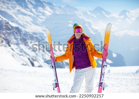 Young active woman skiing in mountains. Female skier with safety helmet, goggles and poles enjoying sunny winter day in Swiss Alps. Ski race for adults. Winter and snow sport in alpine resort. Royalty-Free Stock Photo #2250902257