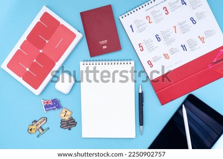 Vacation, trip or holiday to planning New Zealand concept - Public Holiday calendar with passport, notepad, pen, earphone and tablet on blue background. Top view flat lay copy space.