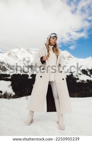 Girl in the snowy Alps shows fashion, snow and mountains, ski fashion