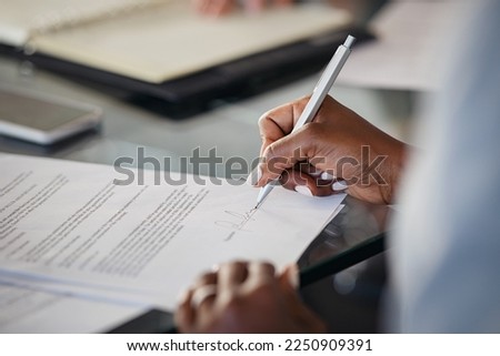Close up of hand of black business woman signing agreement document in modern office. African american businesswoman signing contract. Woman sealing paperwork after deal and successful negotiations.