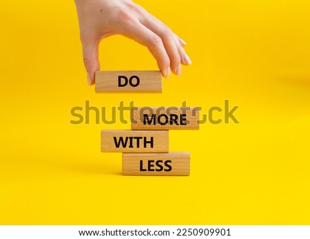Do more with less symbol. Concept words Do more with less on wooden blocks. Beautiful yellow background. Businessman hand. Business and Do more with less concept. Copy space. Royalty-Free Stock Photo #2250909901