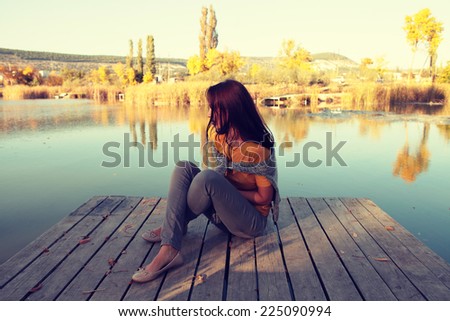 pretty girl sitting by the lake with a toned with an instagram like filter Royalty-Free Stock Photo #225090994