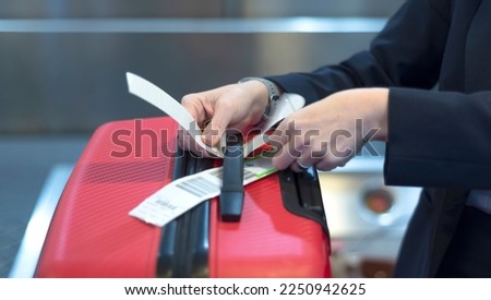 check-in employee attaches a luggage tag to suitcase of passenger - closeup of hands 