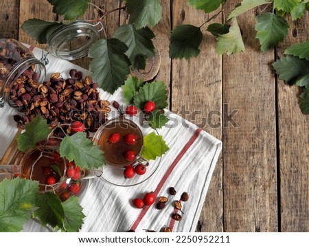 Tea with fresh and dried hawthorn berries in a glass cup on a wooden ancient background. Medicinal soothing herbal tea. Space for text. Alternative folk medicine concept. Royalty-Free Stock Photo #2250952211