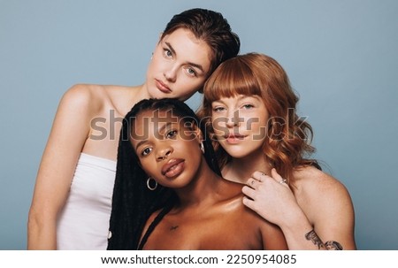 Women with different skin tomes looking at the camera in a studio. Group of confident young women feeling comfortable in their natural skin. Three body positive young women standing together. Royalty-Free Stock Photo #2250954085