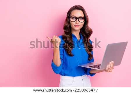Photo of adorable lovely woman with curly hairdo dressed blue blouse directing empty space hold laptop isolated on pink color background