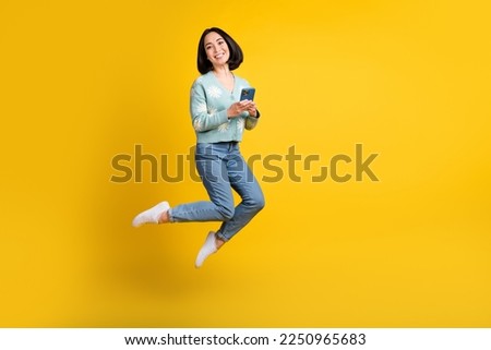 Full size photo of adorable nice woman bob hairstyle dressed blue pullover hold phone typing email isolated on yellow color background