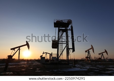 Oil field, tower pumping unit in the evening