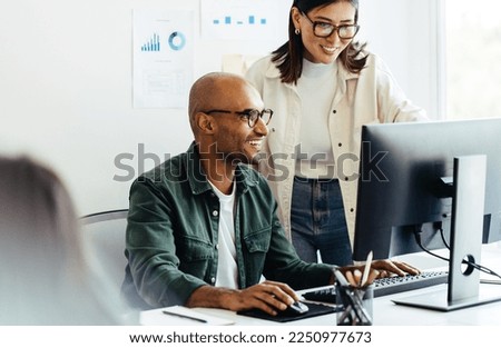 Web developers using a computer together in a creative office. Two business people working on a new software developing project in an office.