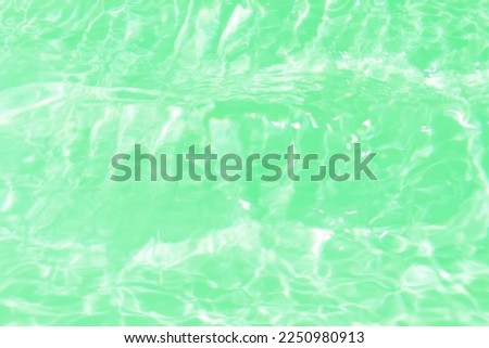 Defocus blurred transparent green colored clear calm water surface texture with splashes and bubbles. Trendy abstract nature background. Water waves in sunlight with caustics. Green water shinning 