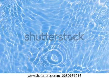 Defocus blurred transparent blue colored clear calm water surface texture with splashes and bubbles. Trendy abstract nature background. Water waves in sunlight with caustics. Blue water shinning 