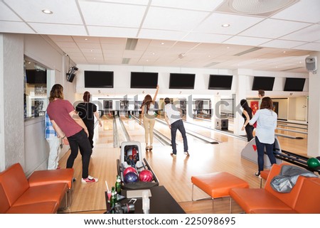 Rear view of young friends bowling in club