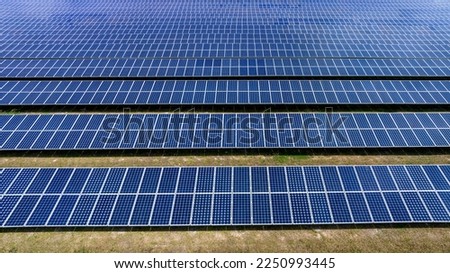  Blue Solar panel farm or solar power plantation.  Alternative renewable energy with photovoltaic cell industry. Green energy technology for future world concept, drone point of view
