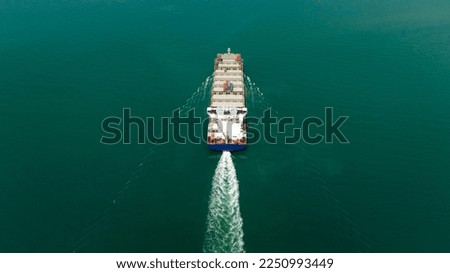 ship transport sailing full speed in green sea photograph from drone camera aerial view,