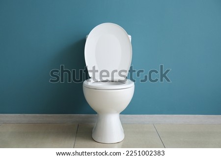 Ceramic toilet bowl near blue wall Royalty-Free Stock Photo #2251002383