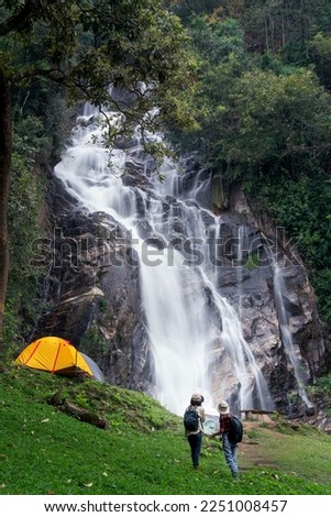 woman traveller walk togather Tent and camping with Mae Tia waterfall and mountain background at inthanon national park in Chiang mai, Thailand, un seen travel point for camping and relax in holiday