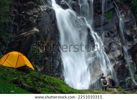 woman traveller walk together Tent and camping with Mae Tia waterfall and mountain background at inthanon national park in Chiang mai, Thailand, un seen travel point for camping and relax in holiday Royalty-Free Stock Photo #2251010315