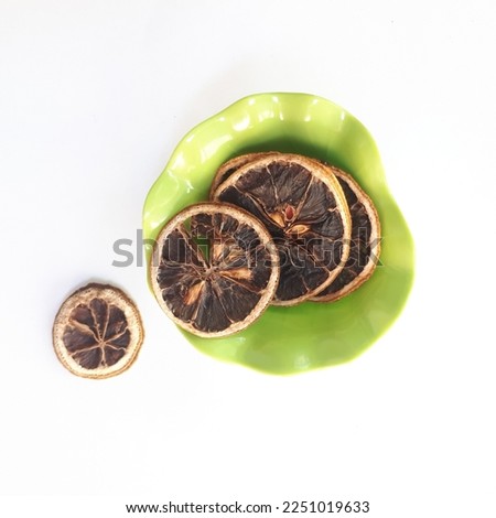 dried lemon with a green plate on isolated white background