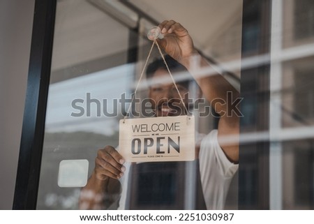 Young Asia coffee shop owner business man in apron with open sign at door shop.