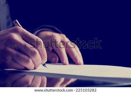 Close up Human Hand Signing on Formal Paper at the Table on Black Background. Retro Filter Effect. Royalty-Free Stock Photo #225103282