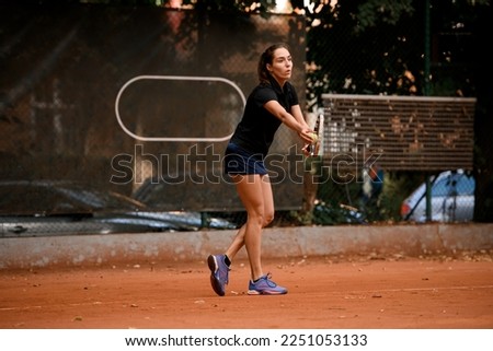 Young handsome female tennis player standing on outdoors court and holding tennis ball while preparing for serving