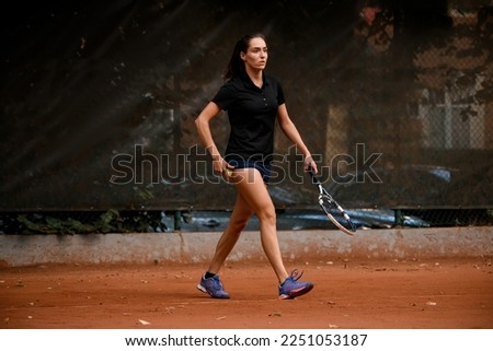 view on beautiful athletic walking female tennis player with racket in her hand. Training at outdoor tennis court.
