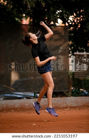 side view of active sporty bouncing woman tennis player with tennis racket in hand doing pitch
