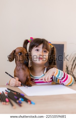 cute little girl draws with her friend dog dachshund. Children and animals. Dog Friendly. High quality photo