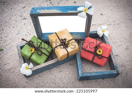 gift box and vintage style empty photo frame  lying on a sea sand decorated with flower background. Space for your text.vintage color tone