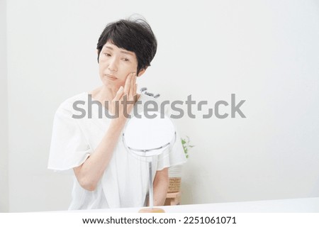 Asian senior woman looking in the mirror at home Royalty-Free Stock Photo #2251061071