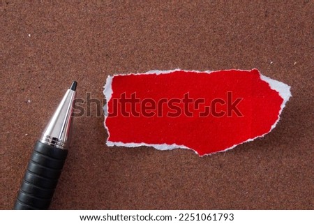 Blank paper with pen on brown background. Top view of red paper piece with copy space.