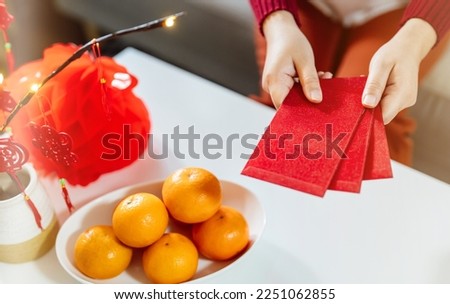 Asian Woman giving red envelope for Lunar New Year celebrations. Hand hold red packet.