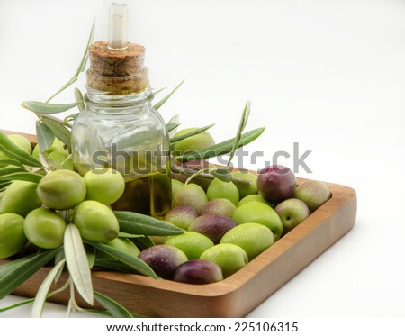 Extra virgin olive oil surrounded by freshly harvested olives