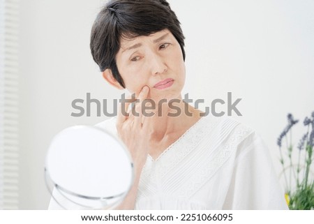 Asian senior woman looking in the mirror at home Royalty-Free Stock Photo #2251066095