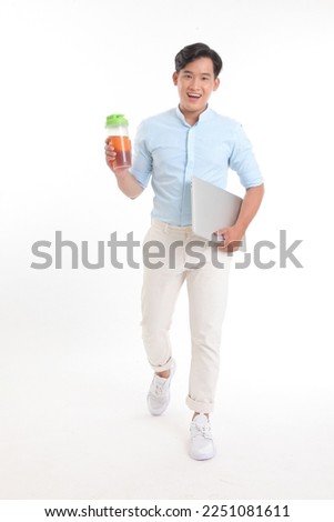 Portrait full length photo of a young Asian handsome male student, with a laptop in hand, smart casual outfit, isolated on white background.