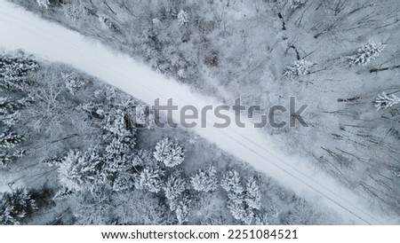 Aerial view of a winter road through the snowy boreal forest Royalty-Free Stock Photo #2251084521