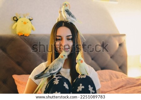 Beautiful woman with birds.Girl with parrots.Love for birds.Cockatiel parrots pets.Portrait of a woman with a parrot.The birds sit on the woman.Pet cockatiel parrots.Favorite animals.Animal friends. Royalty-Free Stock Photo #2251089783