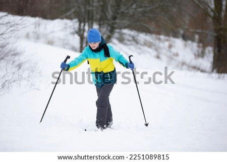 The boy is skiing in the winter forest.