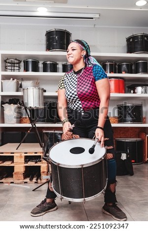 A girl playing a drum with maces surrounded by percussion instruments