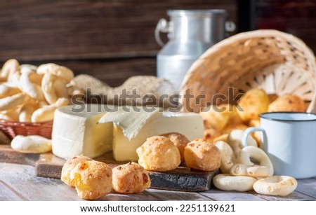 Cheese bread and more, cheese bread, manioc flour cookies and Minas cheese arranged on a rustic wooden surface with accessories, selective focus.
