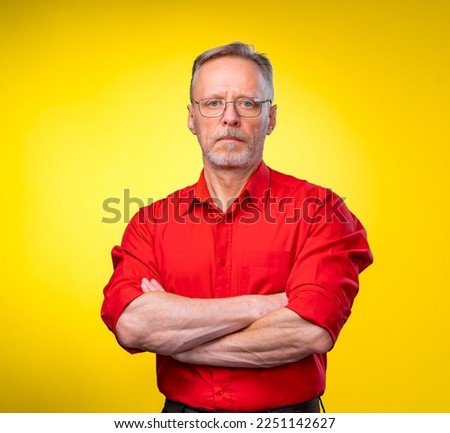 Half length picture of a mid aged business man smiling with arms crossed. solated on a yellow background