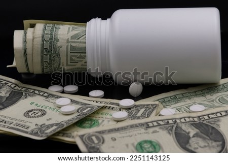 Pills scattered on one dollar bills. Macro image. Costs of medication or drug concept, drug development concept.