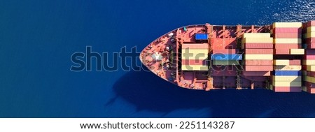 Aerial drone ultra wide photo above truck size container cargo vessel cruising in deep blue sea near commercial port of Piraeus