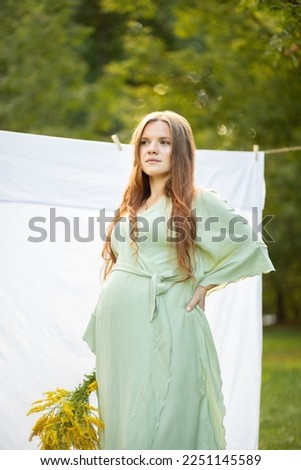 Pregnant woman with big belly, yellow Goldenrod Solidago flowers in hands. White female wears dress.Magic happy pregnancy. Childbirth preparations, emotional connection with baby. Baby shower Vertical