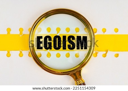 Between two sheets from a notebook on a yellow strip with the inscription - egoism, there is a magnifying glass. Royalty-Free Stock Photo #2251154309