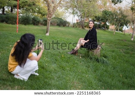 girl in yellow taking a picture of another girl in a party dress in the park 