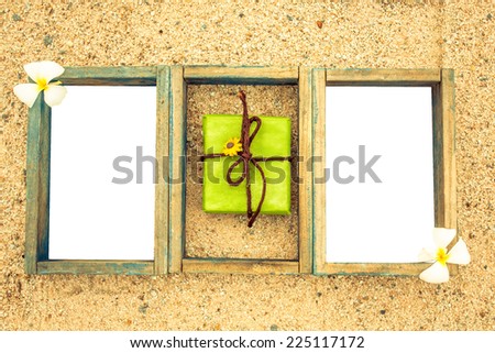 vintage style empty photo frame and flower lying on a sea sand  background. Space for your text.