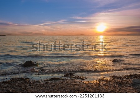 Sunrise over the sea and beautiful cloudscape. Colorful ocean beach sunrise with deep blue sky and sun rays. Sunset at the beach with tall grass. Travel photo, nobody, copy space for text