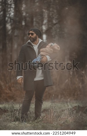 New born family photo shoot in the fall by the woods with father holding newborn